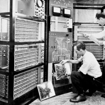 Employees work on the hardware of a room-sized mainframe computer in 1955.